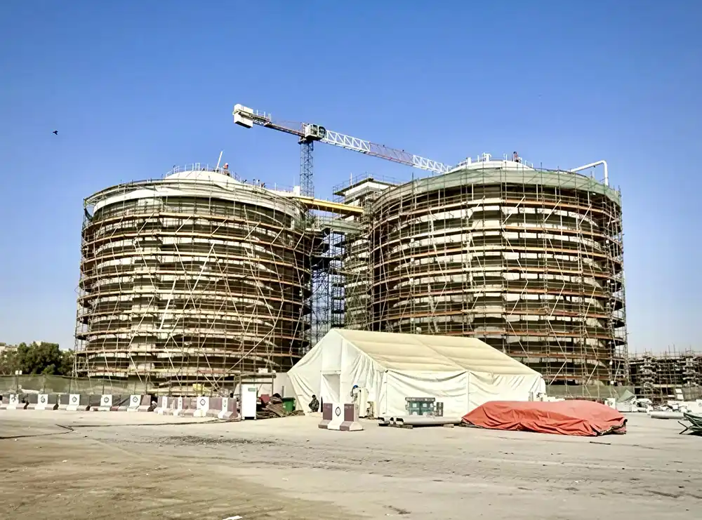 Wide shot of two massive cylindrical digester tanks surrounded by scaffolding at the Al Awir Sewage Treatment Plant during the upgrade project.